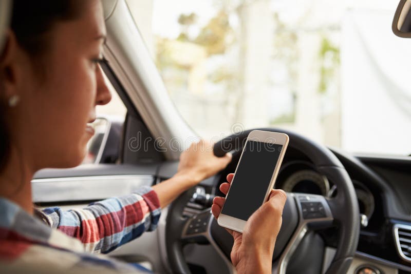 In car view of Hispanic female driver looking at her phone stock photography In car view of Hispanic female driver looking at her phone stock photography