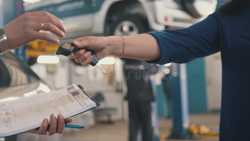 Car workshop - client gives the keys of automobile for mechanic