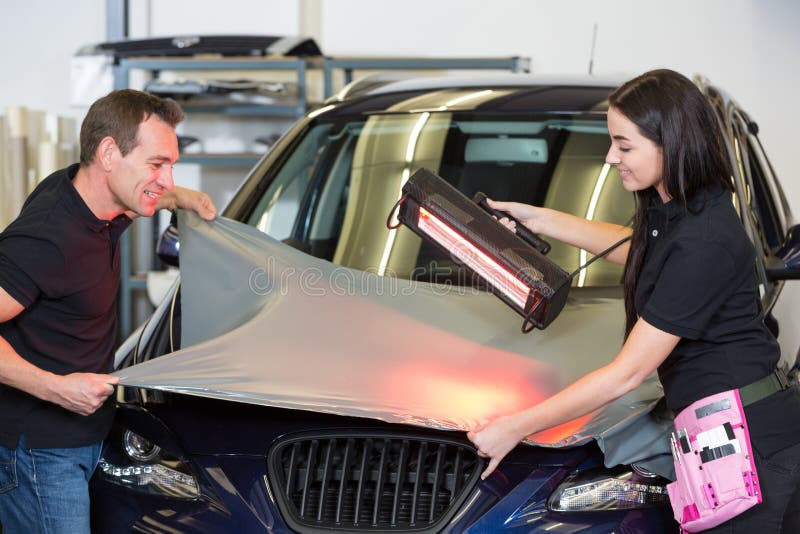 Car wrappers using red light lamp to flatten vinyl film. Or foil