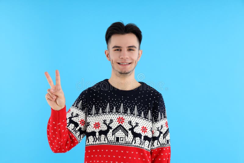 Cara atraente no suéter de natal em fundo azul imagens de stock