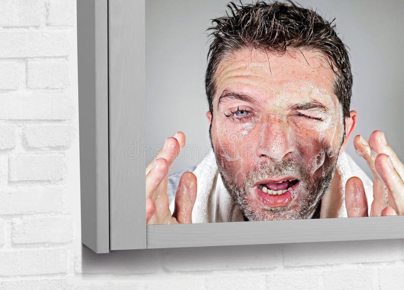 Cara atrativa e engraçada nova da lavagem do homem com sabão com olhos sarnentos e a expressão desarrumado da cara que aplicam cu imagem de stock Cara atrativa e engraçada nova da lavagem do homem com sabão com olhos sarnentos e a expressão desarrumado da cara que aplicam cu imagem de stock