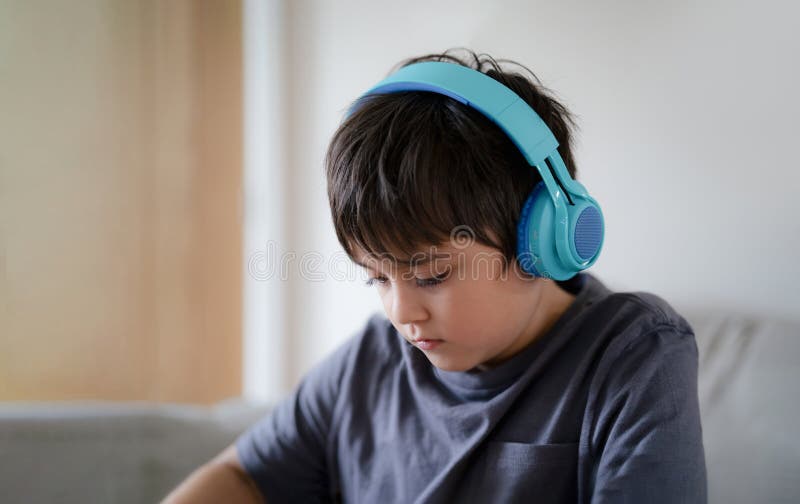 Close Up Cara De Criança Usando Fone De Ouvido Tendo Diversão Jogando Jogo  Online Com Os Amigos, Bonito Menino Da Escola Sentado No Sofá Olhando Para  Cima Assistindo TV Com Rosto Sorridente