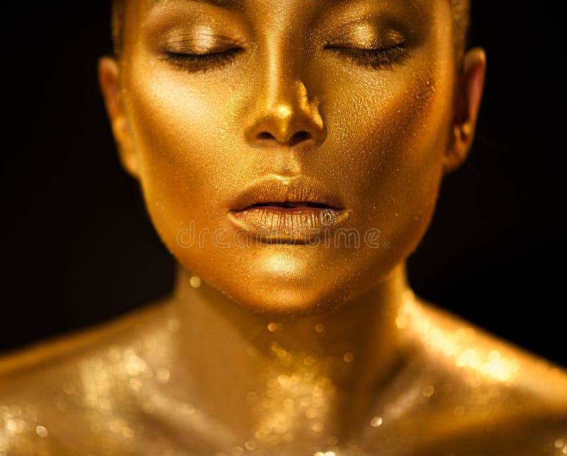 Golden skin woman face. Fashion art portrait closeup. Model girl with holiday golden glamour shiny professional makeup. Gold jewelry, accessories. Golden skin woman face. Fashion art portrait closeup. Model girl with holiday golden glamour shiny professional makeup. Gold jewelry, accessories