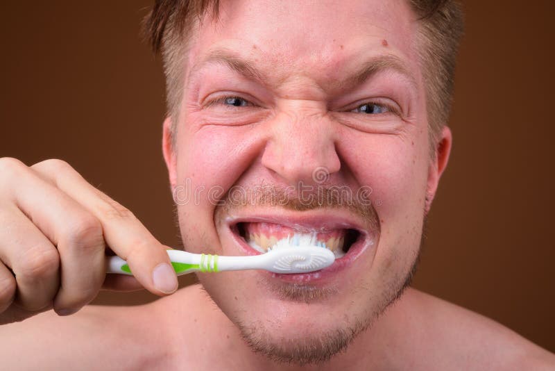 Cara do homem novo que escova seus dentes imagem de stock royalty free Cara do homem novo que escova seus dentes imagem de stock royalty free
