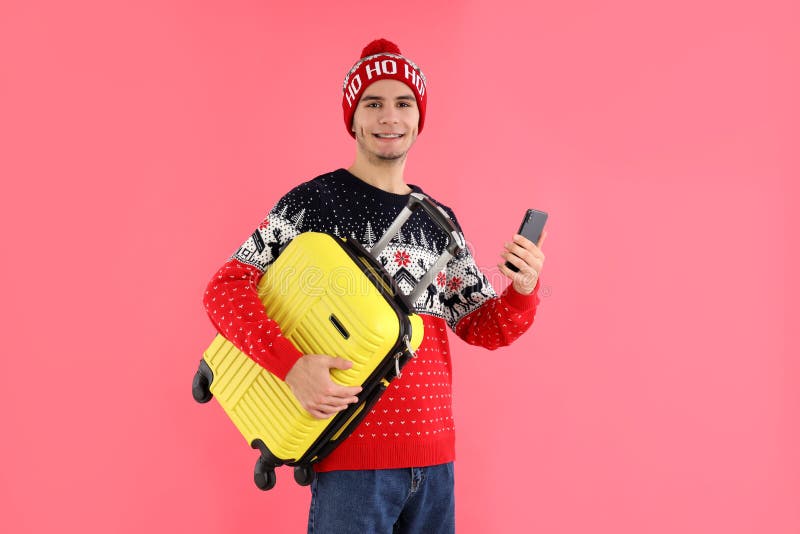 Cara no suéter de natal com mala de bagagem em fundo rosa fotografia de stock
