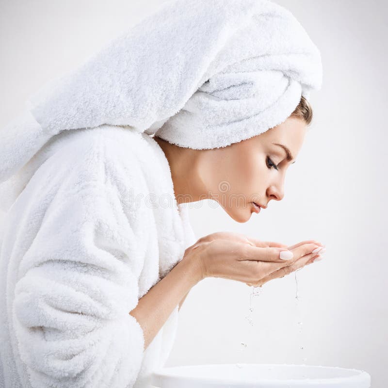 Cara que se lava de la mujer joven con el agua potable foto de archivo libre de regalías Cara que se lava de la mujer joven con el agua potable foto de archivo libre de regalías