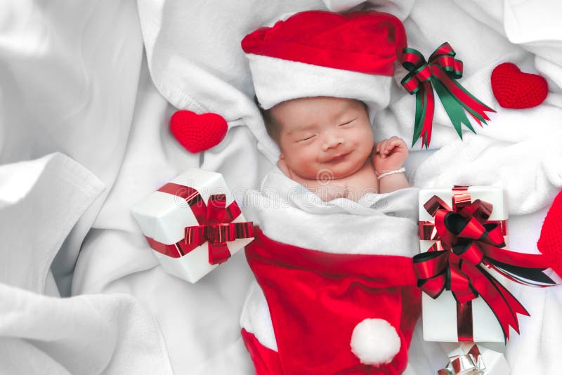 Cara recién nacida del bebé el dormir en sombrero de la Navidad con la caja de regalo de S imágenes de archivo libres de regalías Cara recién nacida del bebé el dormir en sombrero de la Navidad con la caja de regalo de S imágenes de archivo libres de regalías