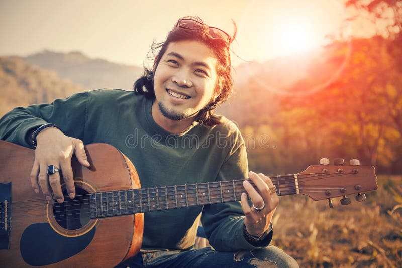 Cara sonriente dentuda del hombre asiático con la felicidad que toca la guitarra y