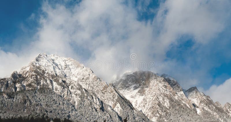 Il illuminato dalla luce del sole nevoso Caraiman Picco sulle Montagne Bucegi dei Carpazi Meridionali, come si è visto dalla città di Buteni in Romania, nel mese di gennaio.