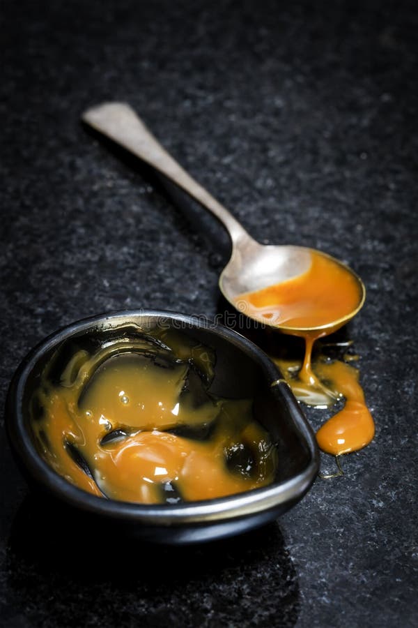 Caramel Sauce in Black Dish with Spoon over Marble with Spill royalty free stock images Caramel Sauce in Black Dish with Spoon over Marble with Spill royalty free stock images