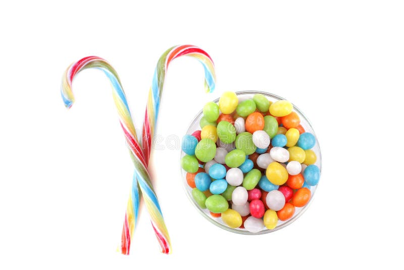 Caramella rotonda multicolore in ciotola di vetro e lecca-lecca su un fondo bianco Isolato immagini stock Caramella rotonda multicolore in ciotola di vetro e lecca-lecca su un fondo bianco Isolato immagini stock