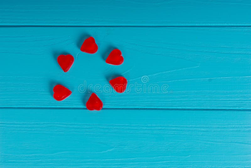 Caramelos rojos de la jalea en la forma de un corazón en la turquesa de madera TA foto de archivo libre de regalías Caramelos rojos de la jalea en la forma de un corazón en la turquesa de madera TA foto de archivo libre de regalías