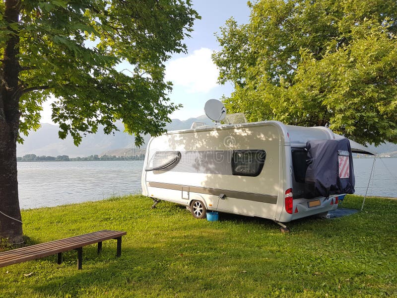 Caravan car on the camping green grass and tress beside lake