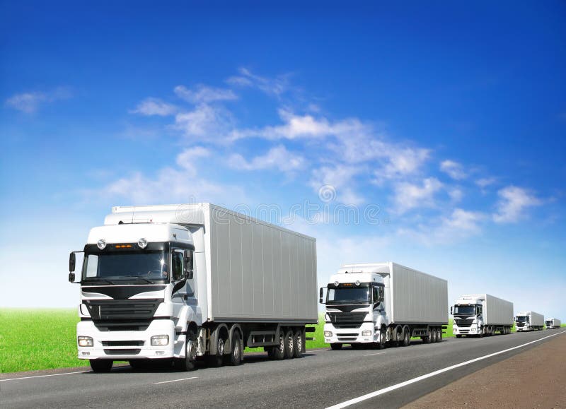 Carovana di camion bianco sul paese in autostrada sotto il cielo blu.