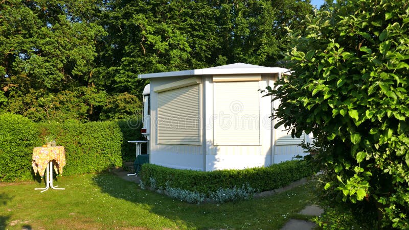 Caravane avec une véranda fixe faite de tissu de tente, fenêtres de glissement en verre et abat-jour sur un terrain de camping al photographie stock Caravane avec une véranda fixe faite de tissu de tente, fenêtres de glissement en verre et abat-jour sur un terrain de camping al photographie stock