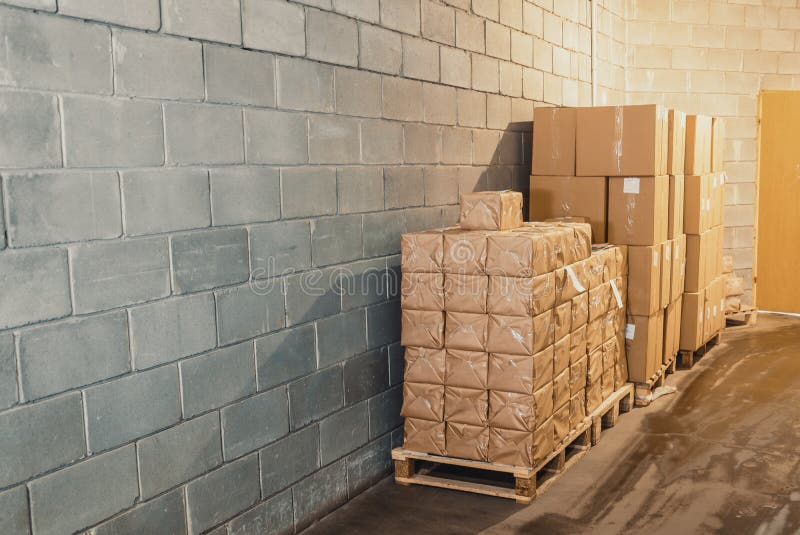 Cardboard Boxes On Pallets In A Warehouse Near The Concrete Wall Stock