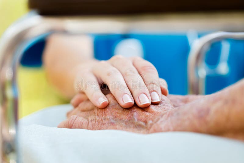 La cura il medico o l'infermiere holding anziani ladys mani in sedia a rotelle.