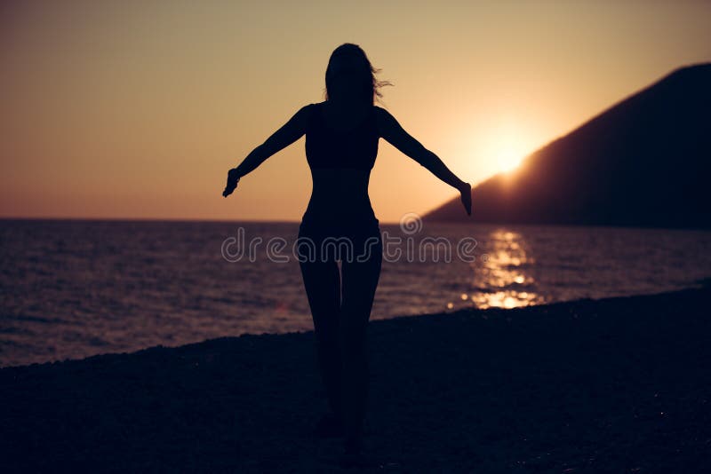 Carefree woman dancing in the sunset on the beach.Vacation vitality healthy living concept.Free woman enjoying freedom feeling hap