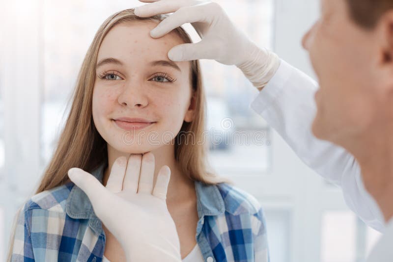 Careful dermatologist examining patient face at work