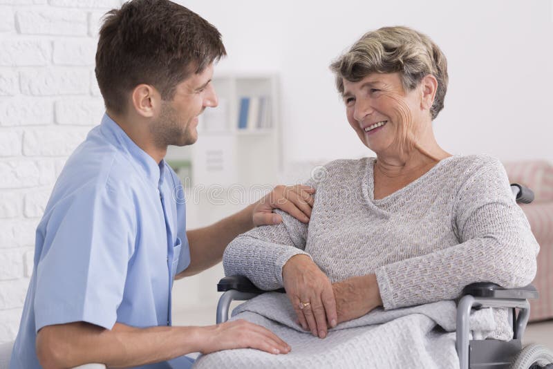 Caregiver comforting elderly woman. Professional caregiver comforting smiling elderly women on wheelchair royalty free stock photos
