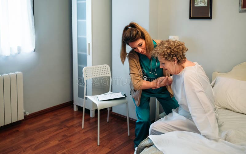 Caregiver helping elderly patient to get out of bed royalty free stock image Caregiver helping elderly patient to get out of bed royalty free stock image