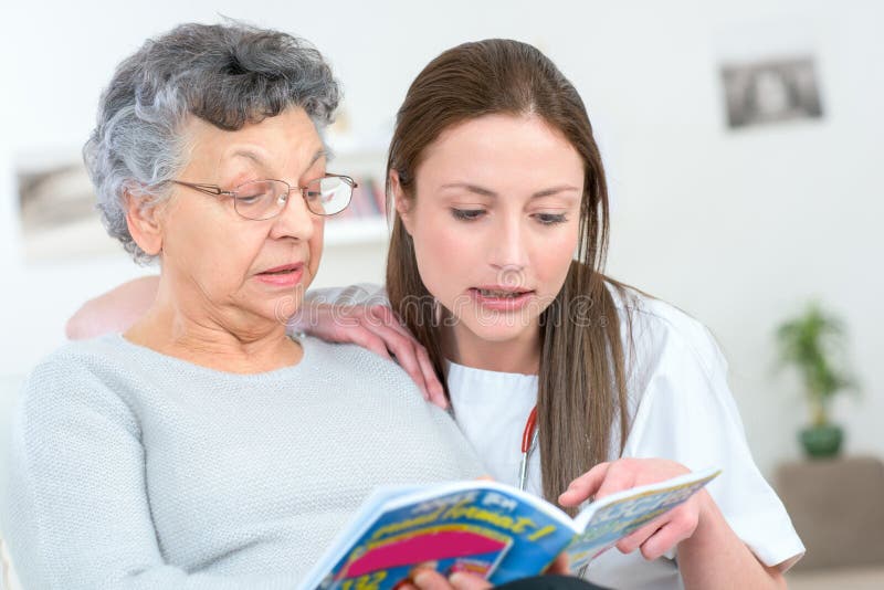 Caregiver reading book with elderly patient stock images Caregiver reading book with elderly patient stock images