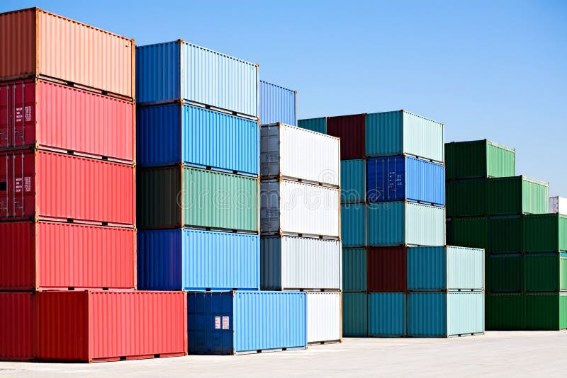 Cargo shipping containers stacked at harbor freight terminal under clear blue sky. Cargo shipping containers stacked at harbor freight terminal under clear blue sky