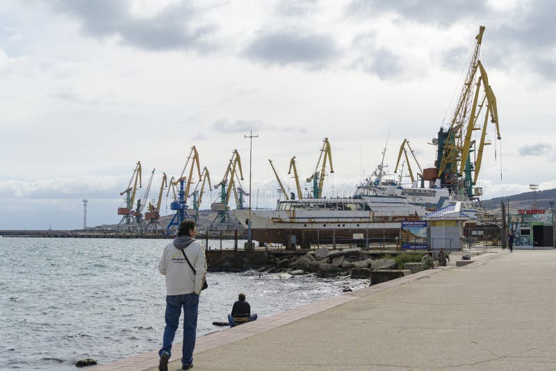 Cargo port of Feodosia with cranes and ships. View from from the city promenade. Feodosia, Crimea stock photo Cargo port of Feodosia with cranes and ships. View from from the city promenade. Feodosia, Crimea stock photo