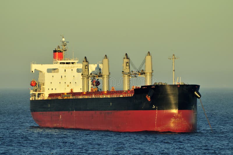 Cargo ship designed for transporting of bulk cargo, making turn on the sea surface