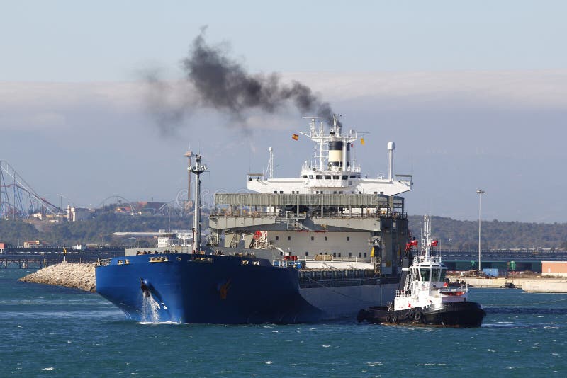 Cargo ship arriving at port, with smoke