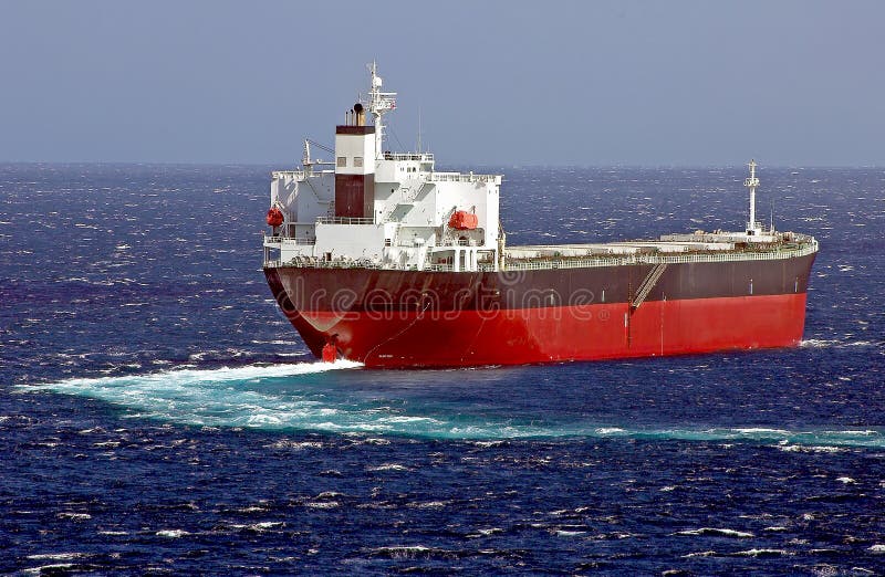 Cargo ship designed for transporting of bulk cargo, making turn on the sea surface