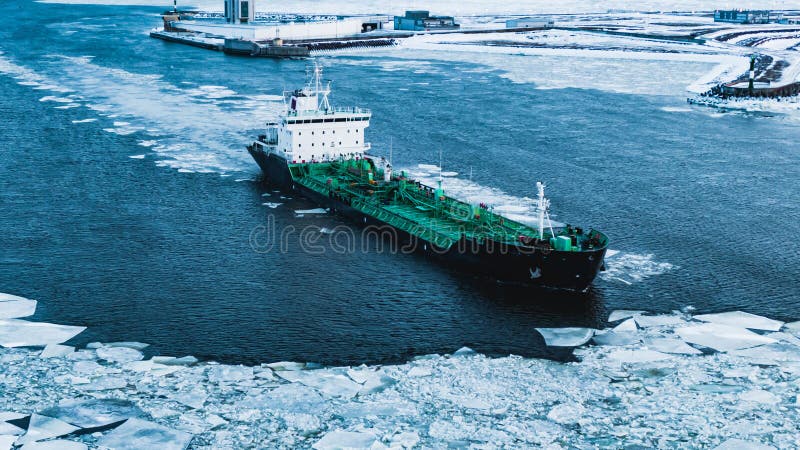 Cargo ship sailing through cold ocean water with broken ice stock photography