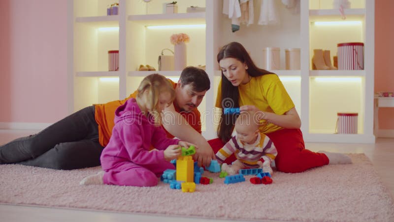 Caring attractive parents with two little daughters playing with toy blocks