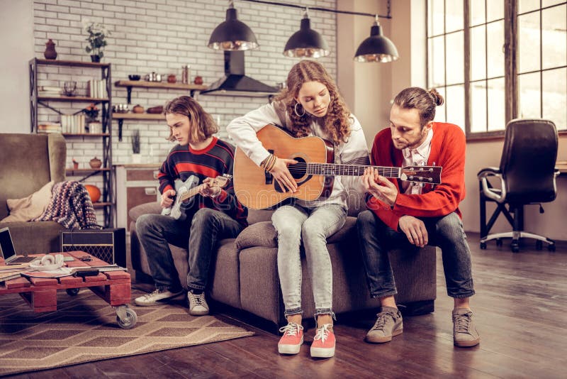 Caring boyfriend helping his beautiful girl playing the guitar stock photo Caring boyfriend helping his beautiful girl playing the guitar stock photo