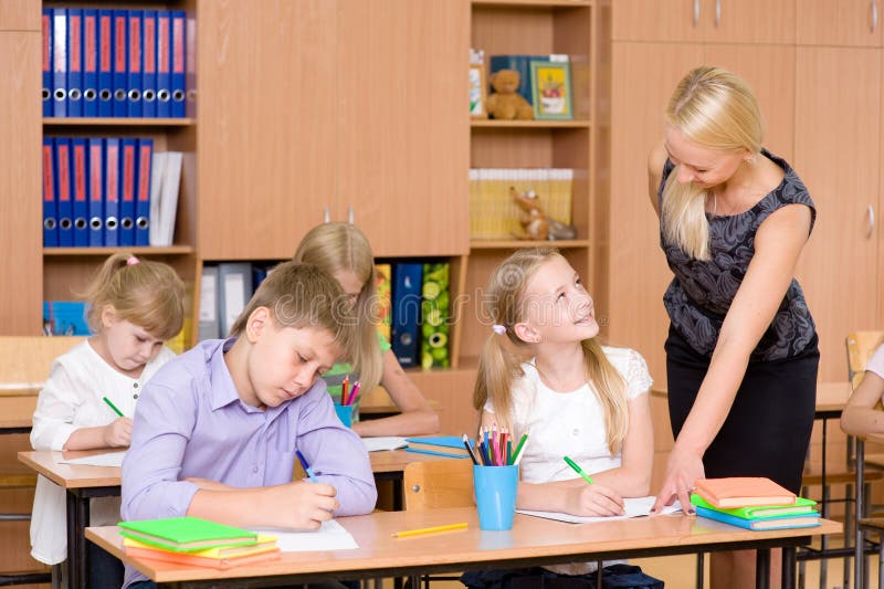 Caring elementary school teacher helping student in classroom stock photography Caring elementary school teacher helping student in classroom stock photography