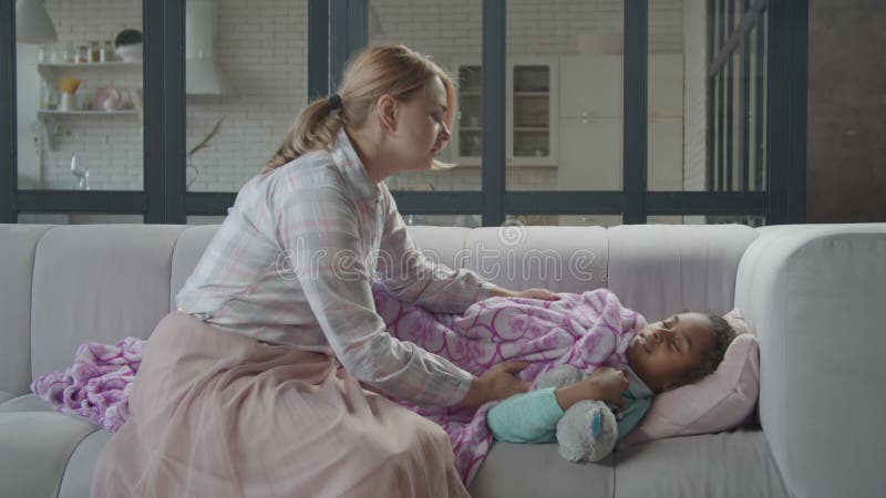 Caring mom consoling sleepy sick child on sofa