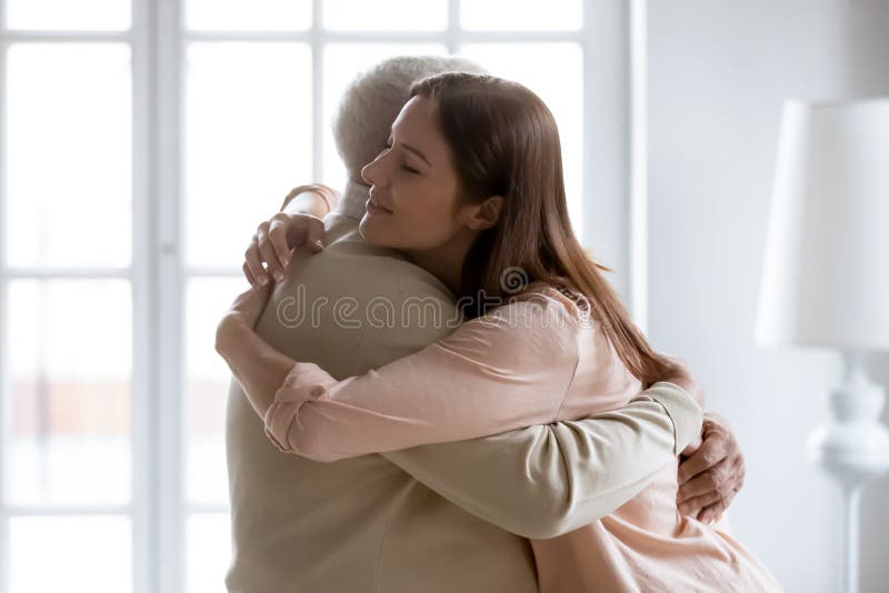 Cariñosa hija mayor y papá viejo abrazándose en casa imagenes de archivo