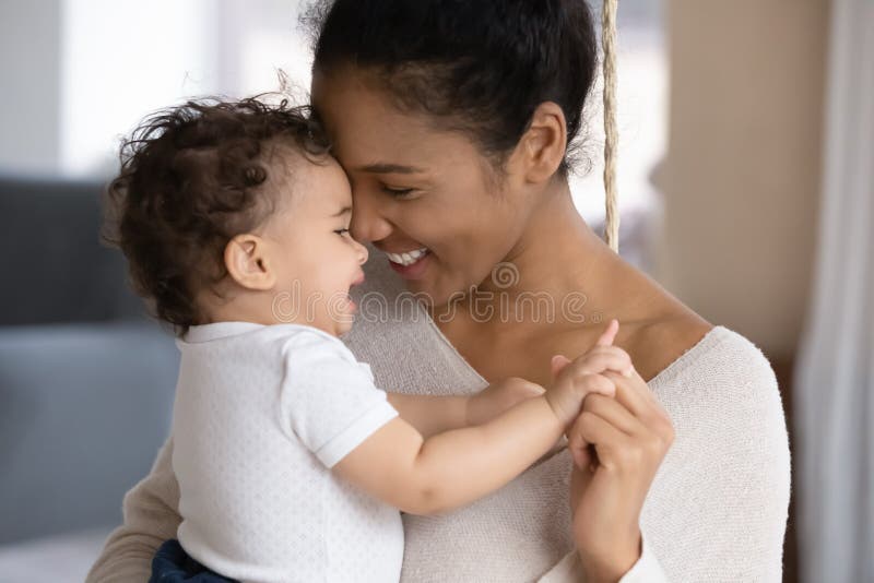 Cariñosa madre birracial abraza a un bebé lindo