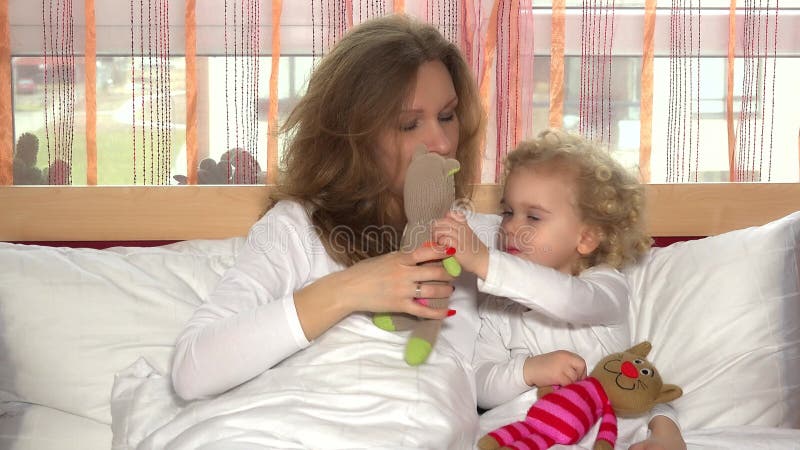 Cariñosa y adorable hija con joven madre jugando con juguetes de gatos