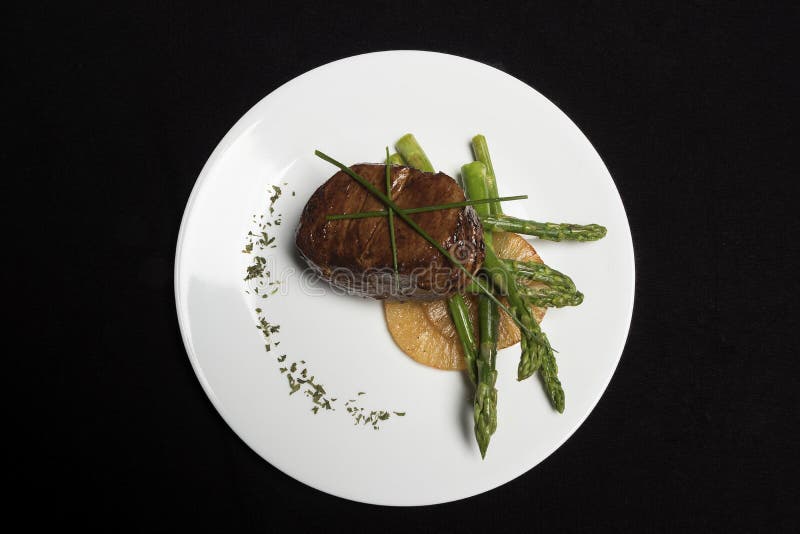 Carne com aspargo e abacaxi na placa branca e no fundo preto imagem de stock Carne com aspargo e abacaxi na placa branca e no fundo preto imagem de stock