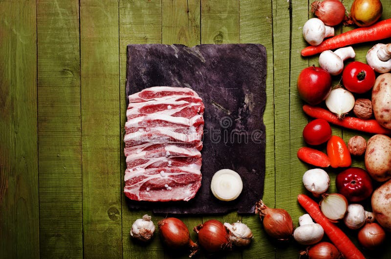 Carne congelada crua no fundo de madeira verde Pescoço cru, veget da carne de porco foto de stock royalty free Carne congelada crua no fundo de madeira verde Pescoço cru, veget da carne de porco foto de stock royalty free