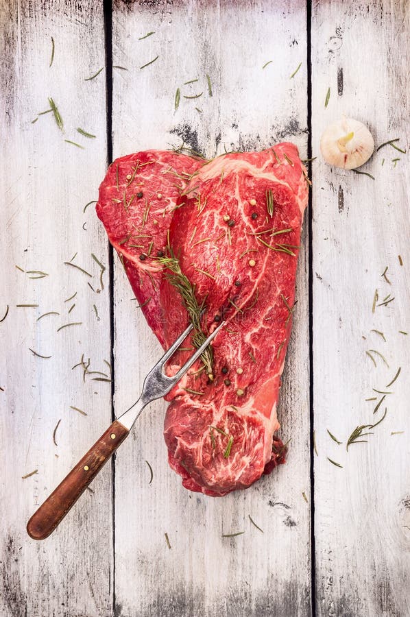Carne crua com a forquilha da carne no fundo de madeira cinzento branco velho imagens de stock Carne crua com a forquilha da carne no fundo de madeira cinzento branco velho imagens de stock