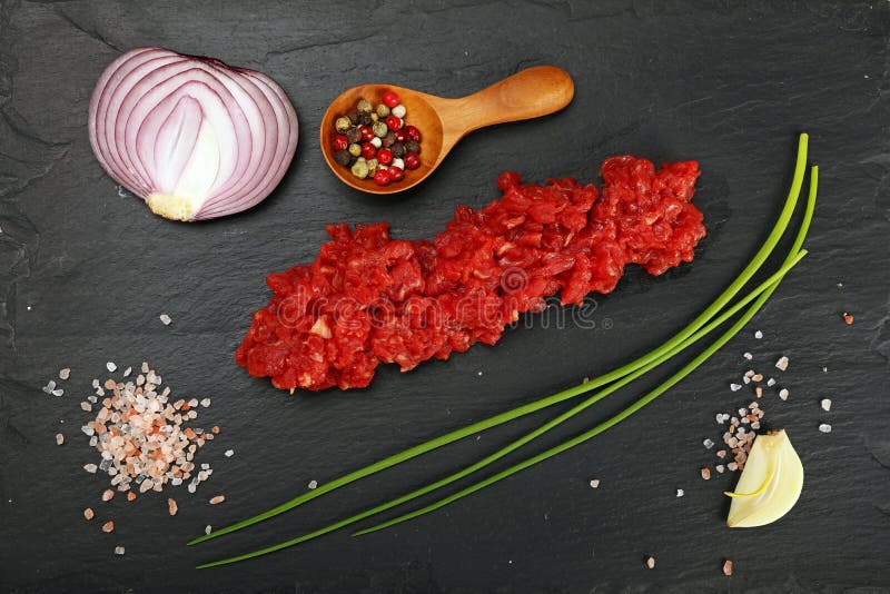 A carne crua triturou a carne e as especiarias na placa preta foto de stock A carne crua triturou a carne e as especiarias na placa preta foto de stock