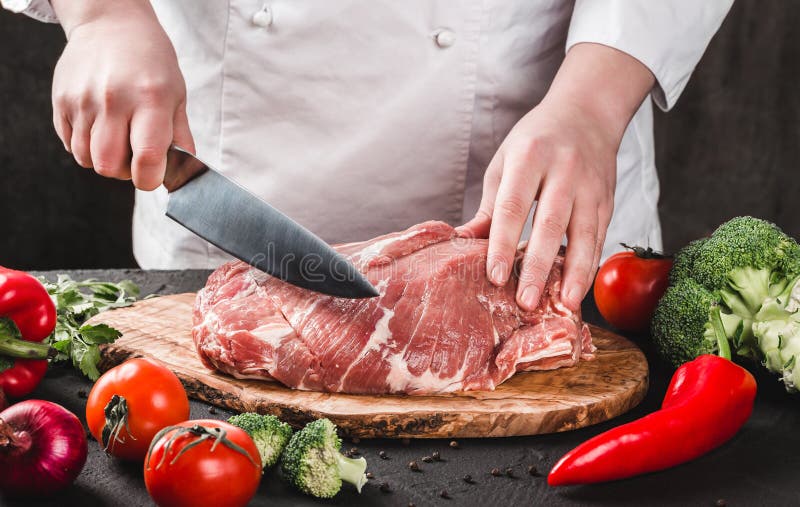 Carne de cerdo del corte de Butcher del cocinero con el cuchillo en la cocina, cocinando la comida foto de archivo Carne de cerdo del corte de Butcher del cocinero con el cuchillo en la cocina, cocinando la comida foto de archivo