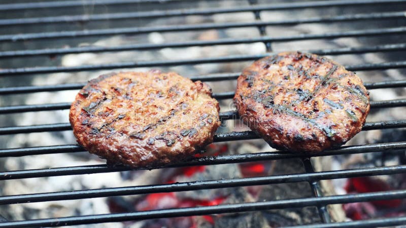 Carne de hamburguesa cocinada en parrilla de carbón vegetal al al aire libre. dolly shot