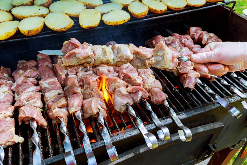 Carne do assado do churrasco no carvão de madeira O homem cozinha o no espeto quente apetitoso em espetos do metal imagem de stock Carne do assado do churrasco no carvão de madeira O homem cozinha o no espeto quente apetitoso em espetos do metal imagem de stock
