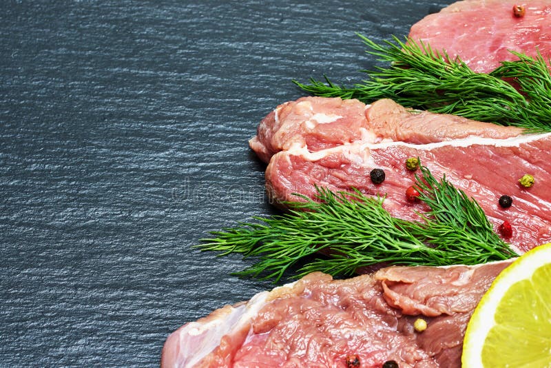 Carne fresca cruda del manzo con un ramoscello di aneto e del limone su un fondo nero fotografia stock Carne fresca cruda del manzo con un ramoscello di aneto e del limone su un fondo nero fotografia stock