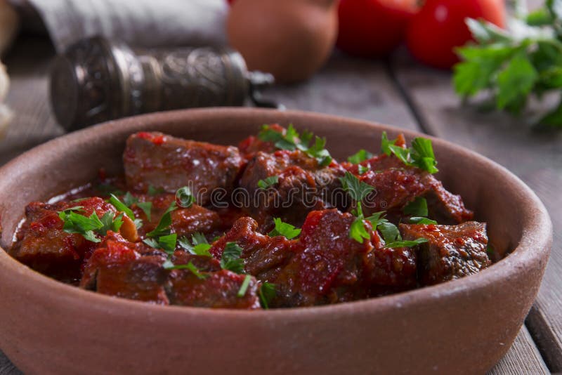 Carne no assado de carne do molho de tomate em uma bacia da argila imagem de stock royalty free Carne no assado de carne do molho de tomate em uma bacia da argila imagem de stock royalty free