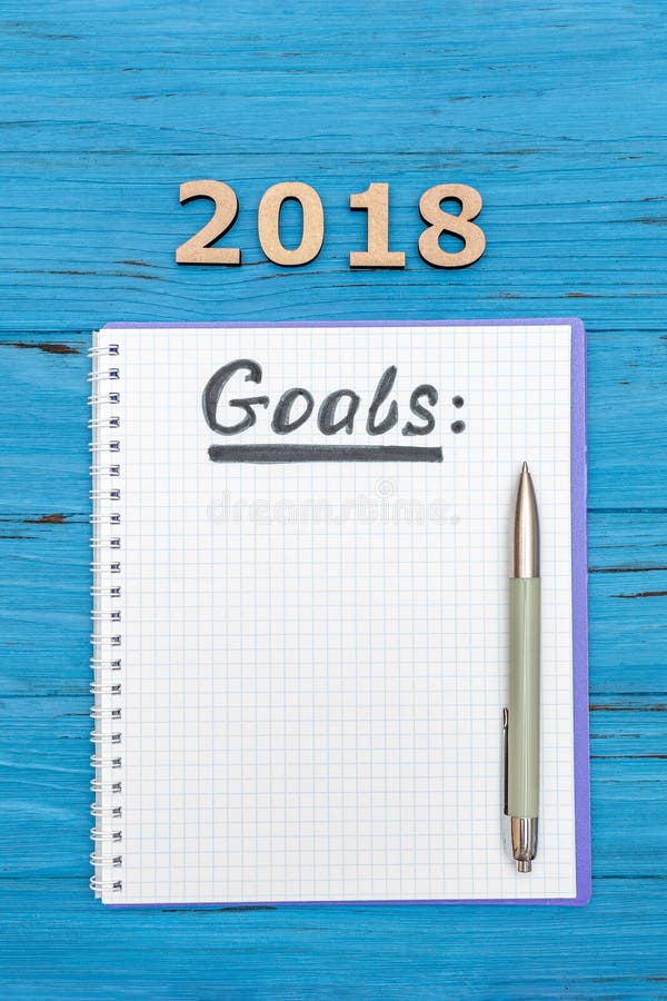 Carnet avec des buts de nouvelles années pour 2018 avec un stylo et des numéros 2018 sur une table en bois bleue images stock Carnet avec des buts de nouvelles années pour 2018 avec un stylo et des numéros 2018 sur une table en bois bleue images stock