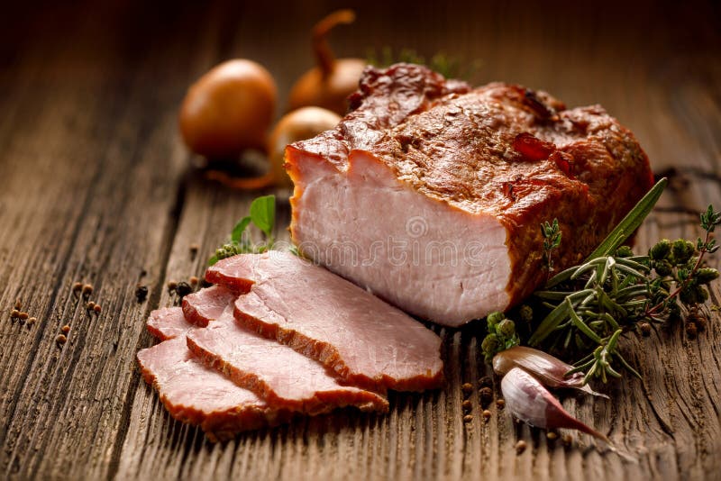 Carni affumicate, lonza di maiale affumicata affettata su una tavola di legno con l'aggiunta delle erbe fresche e spezie aromatic fotografia stock libera da diritti Carni affumicate, lonza di maiale affumicata affettata su una tavola di legno con l'aggiunta delle erbe fresche e spezie aromatic fotografia stock libera da diritti